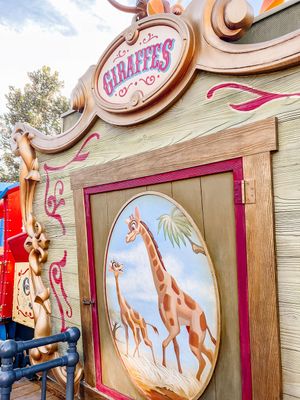 A whimsical carnival-style game display featuring colorful giraffe illustrations and pink decorative elements.