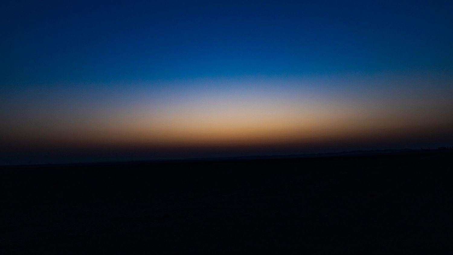 Ethereal twilight horizon with deep blue sky fading into warm orange colors at dusk.