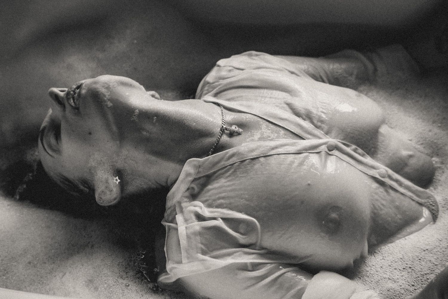 A cinematic black-and-white photo of a woman in a bathtub, wearing a wet, translucent shirt -  sense of vulnerability and deep introspection