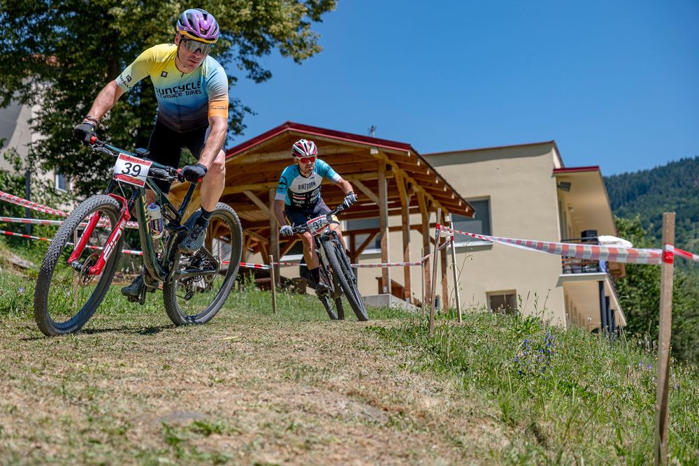 Dvaja horskí cyklisti v zákrute počas pretekov v Hornej Vsi. cyklistika, horská cyklistika, preteky, Kremnica, športové podujatie, outdoor
