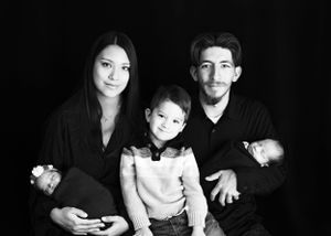 Black and white studio portrait of a family of five posing together against a dark background. #Twins #NewbornPhotography #Carlsbad #Roswell