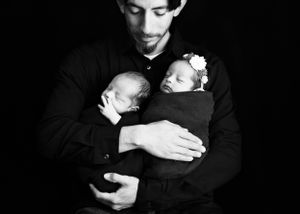 Dad gazing down at twin newborns in black and white photo. #RoswellNewbornphotographer #CarlsbadNM #NewMexicoNewbornPhotographer #Artesia