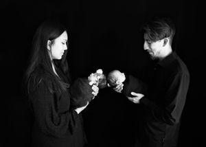 Two people in black clothing stand in darkness as each holds twin babies. #Twinfamilyphotos #CarlsbadNMPhotographer #Twinnewbornphotos