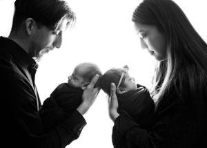Two people holding a baby in silhouette black and white style portrait highlighting loving parental tenderness. #Twinphotographer #Carlsbad