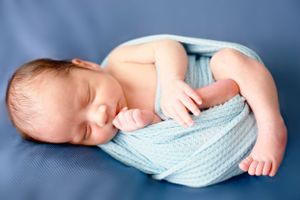 Sleeping newborn swaddled in soft light blue blanket curled up on blue background. #NewbornPictures #CarlsbadNM #Photographer #RoswellNM