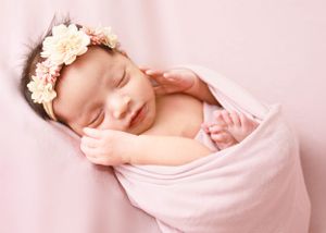 Peaceful sleeping newborn swaddled in soft pink blanket wearing delicate floral crown headband.#NewbornPictures #CarlsbadNM #Photographer