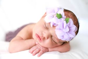 newborn girl with purple floral headband lays sleeping. #NewbornPhotographer #NewbornPictures #CarlsbadNM #roswellNM #ArtesiaNM #Baby