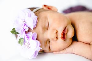 newborn girl with purple floral headband lays sleeping. #NewbornPhotographer #NewbornPictures #CarlsbadNM #roswellNM #ArtesiaNM #Baby