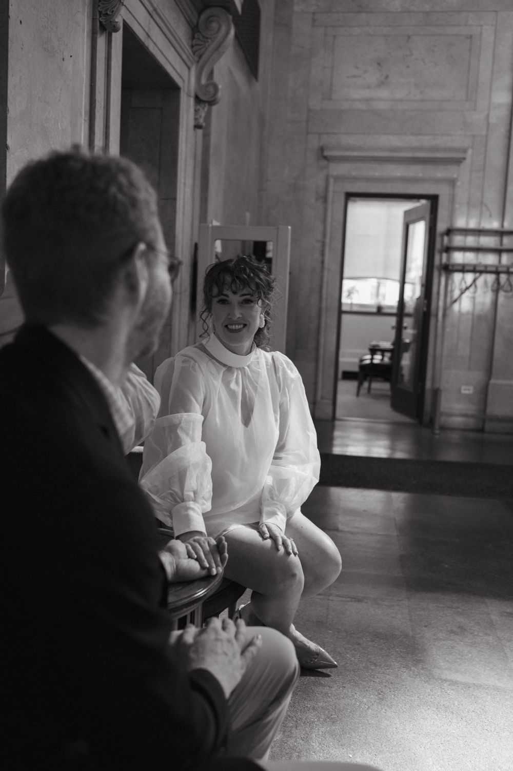 Two people having an intimate conversation in a historic interior with ornate architectural details.