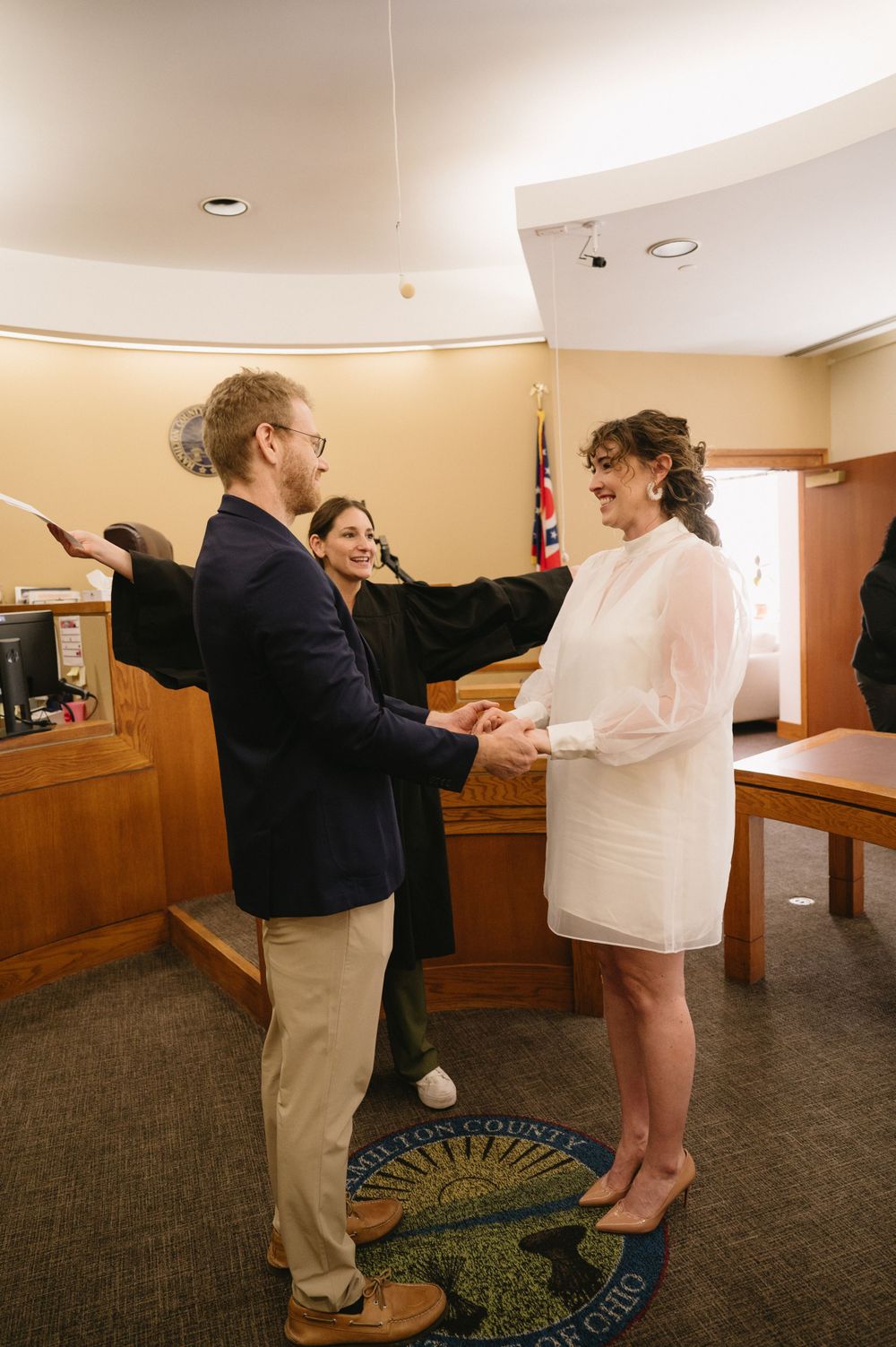 A joyful moment during a courthouse wedding ceremony with the couple holding hands.