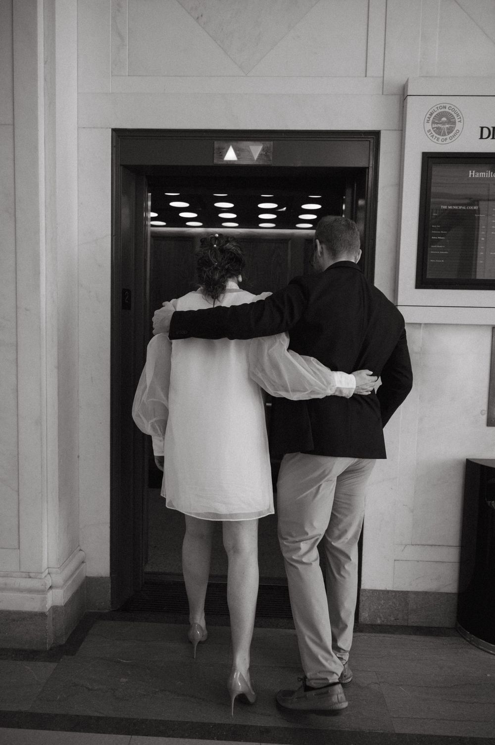 A couple walking into an elevator together in black and white photography.