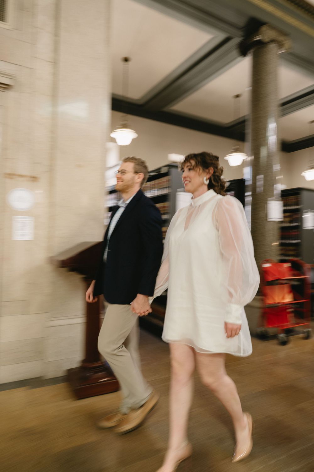 A couple in casual formal wear walking through an indoor space with motion blur effect.
