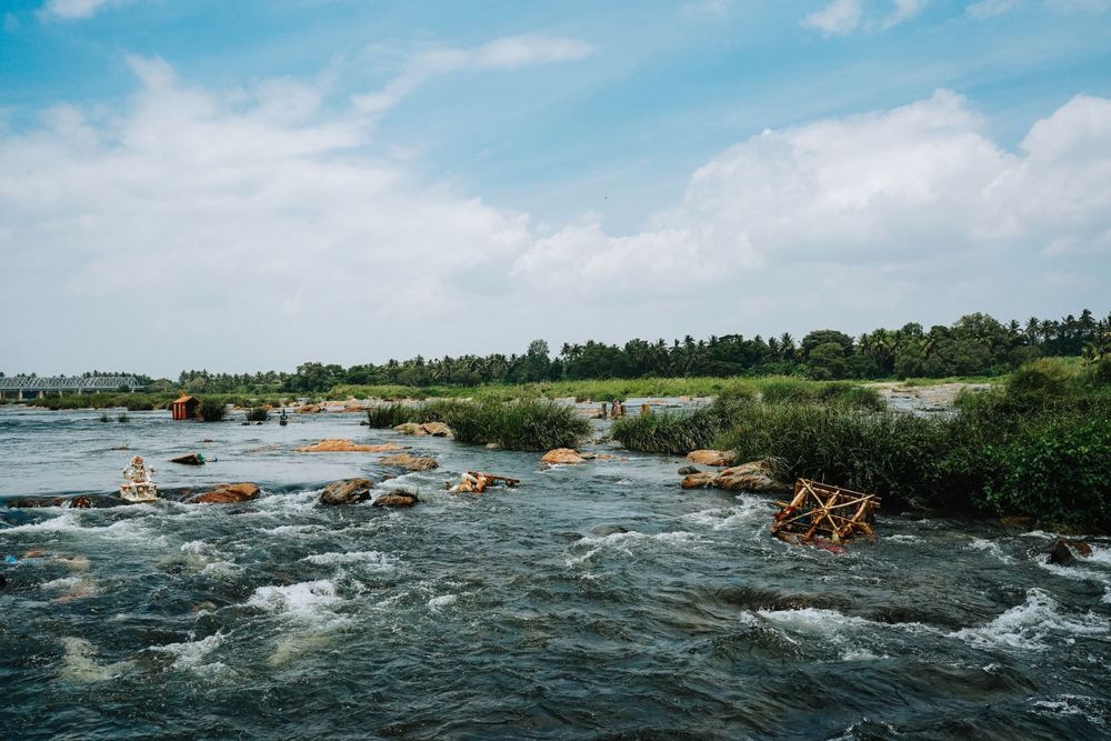 Wide angle view of rocky rapids in a flowing river surrounded by green vegetation.