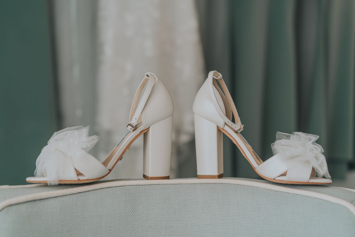 Elegant white bridal shoes with floral details and block heels on display.