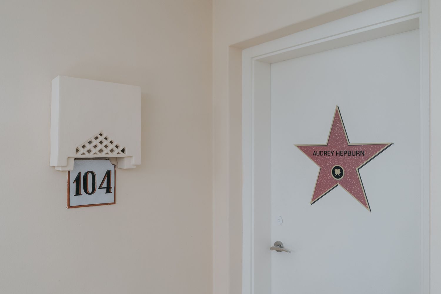 Hotel room 104 with decorative star sign on white door.