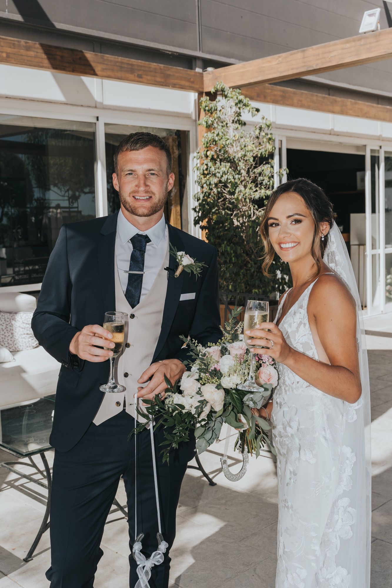 Newlyweds toast with champagne glasses at a modern wedding venue.