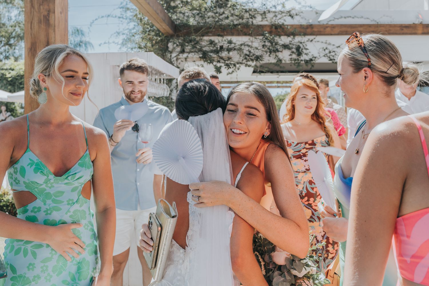 Wedding guests in colorful summer dresses enjoying festivities at an outdoor reception.