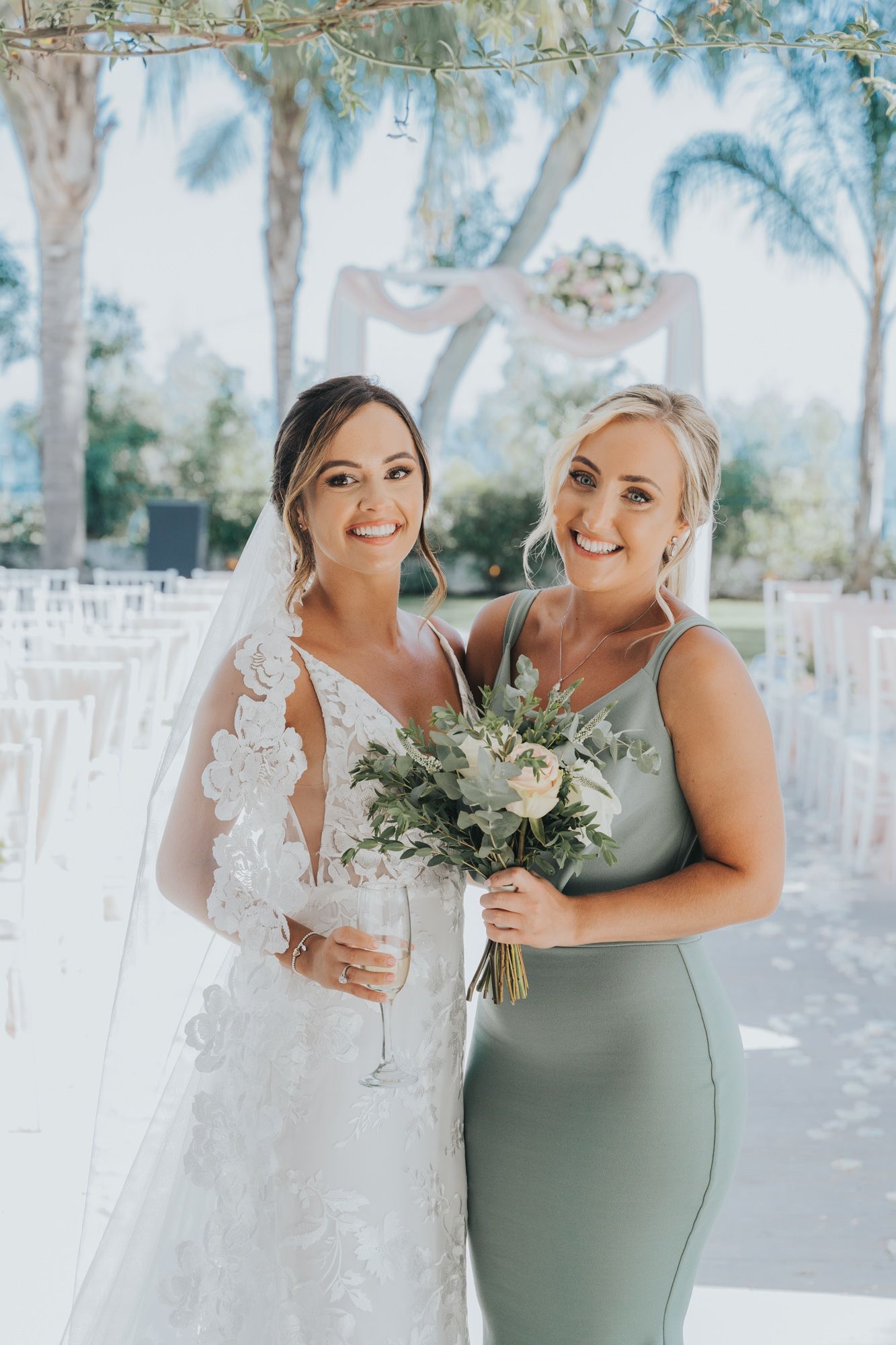Elegant wedding party portrait with sage green bridesmaid dress and white floral bouquet.