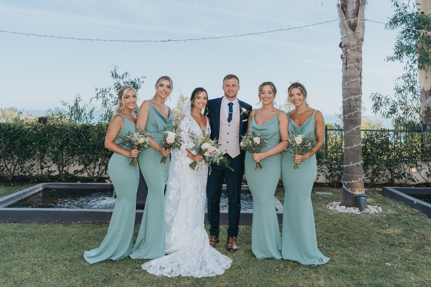 Wedding party poses together outdoors in coordinating mint green dresses.