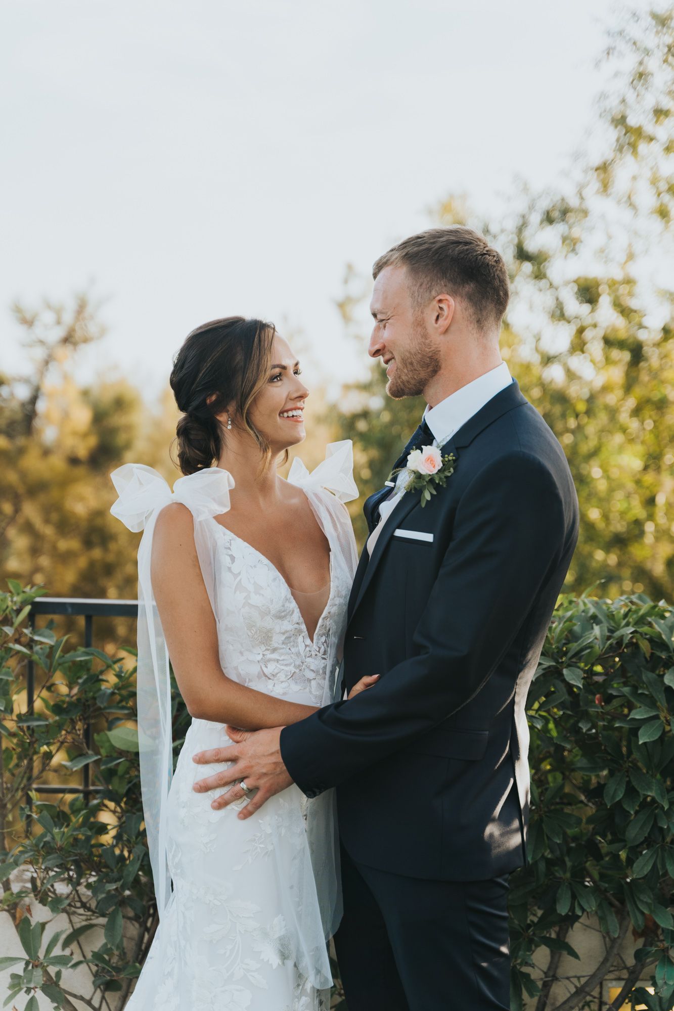 Romantic outdoor wedding portrait with lush greenery background.
