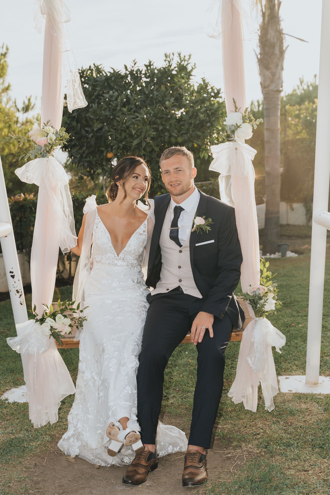 Elegant wedding portrait under white fabric draped posts with garden backdrop.