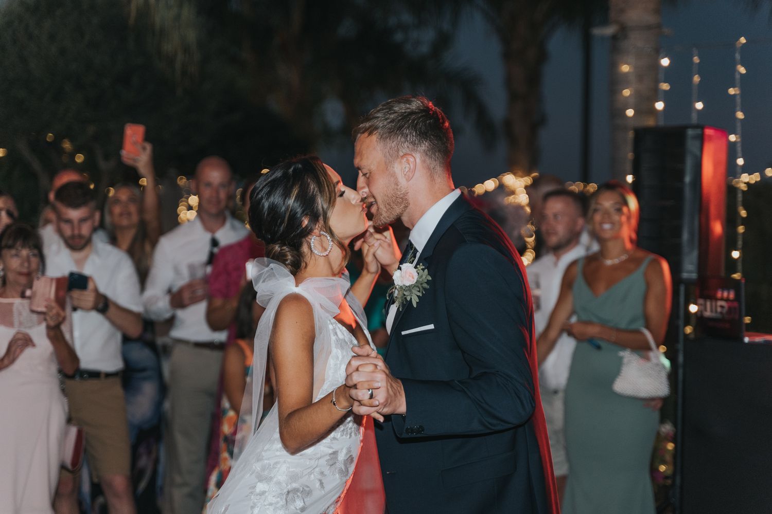 A couple shares an intimate moment during their first dance at a twilight wedding reception.