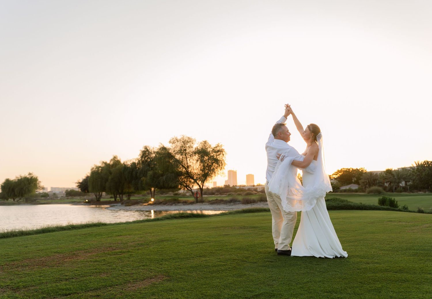A couple shares an intimate moment at dusk on stone steps surrounded by palm trees and Mediterranean architecture.