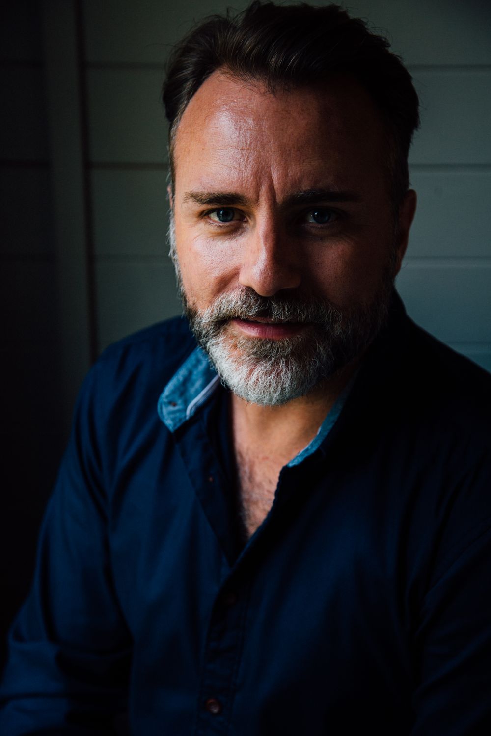 Dramatic portrait photo with moody lighting and dark blue tones.