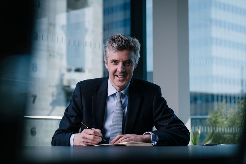 Business professional seated at desk in modern office with city skyline view.