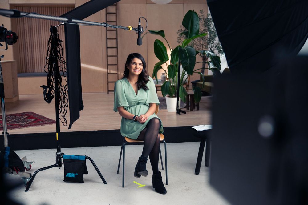 Behind-the-scenes photo of recording studio with lighting equipment and indoor plants.