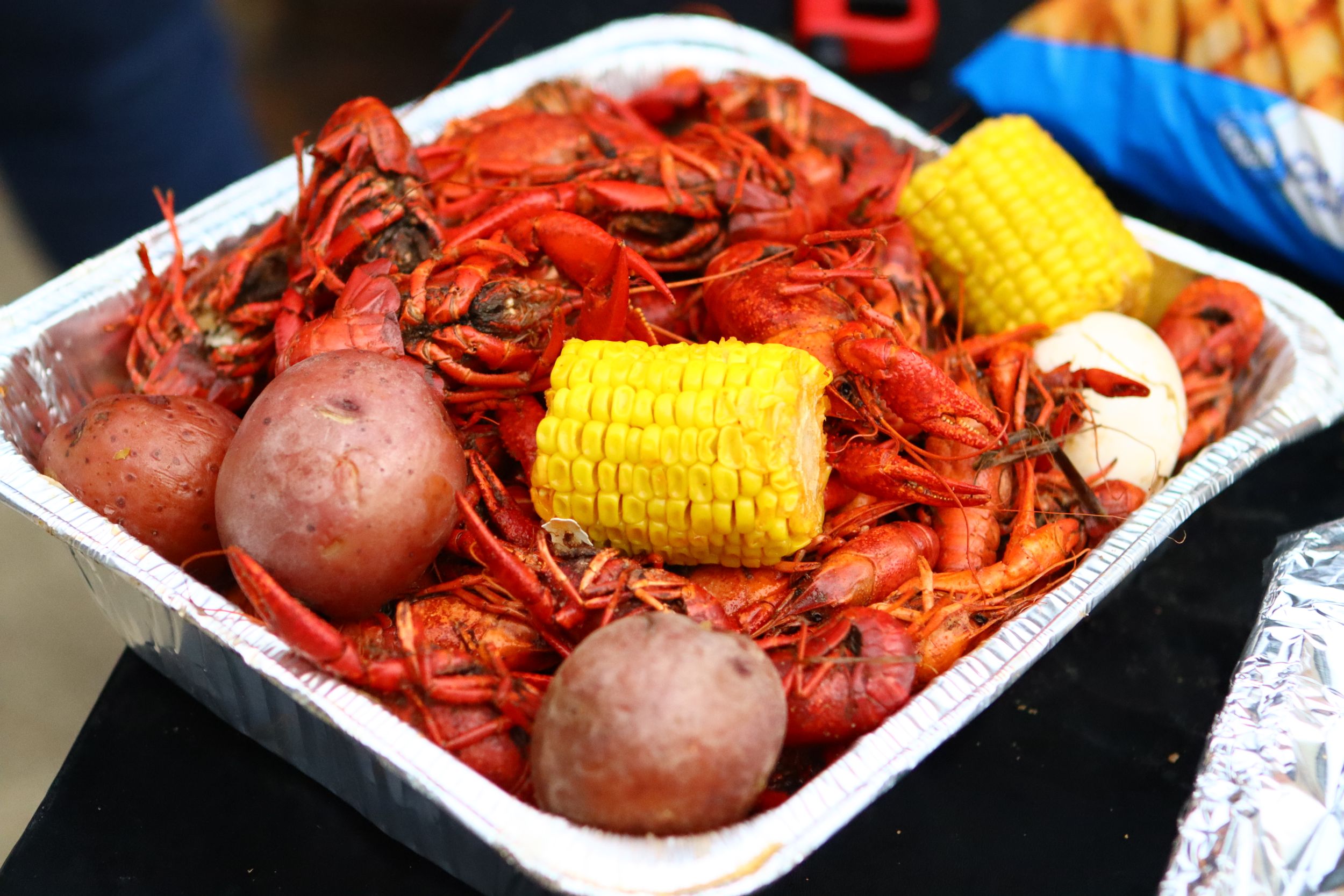 Fresh boiled crawfish with corn and potatoes served in a white container.