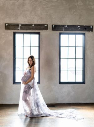 Person in flowing dress poses between industrial windows.