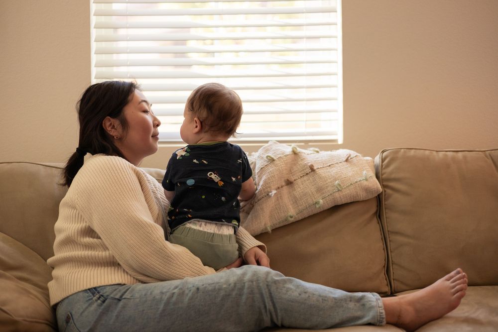 Intimate moment between mom and toddler on sitting on the couch sharing a look in this cozy and warm in-home session in Murrieta, CA.