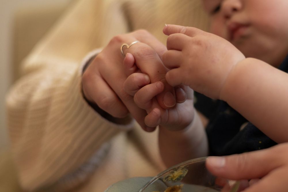 Close-up of toddler boy grasping his mother's fingers in a warm and nostalgic motherhood in-home session in Murrieta, CA.