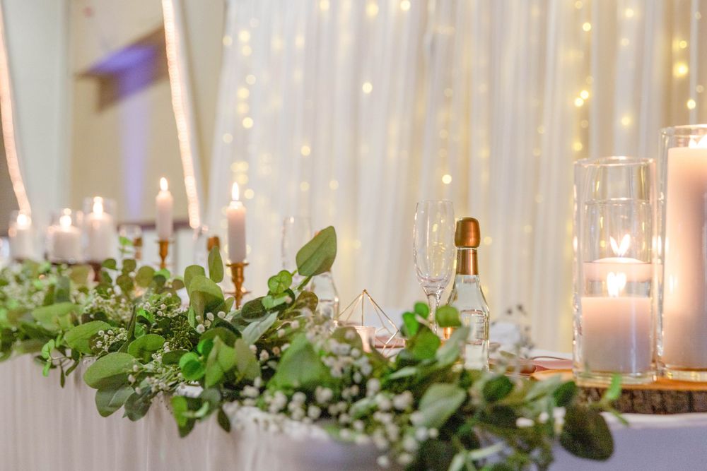 Wedding reception decor with eucalyptus garland, candles, and twinkling string lights creating an elegant ambiance.