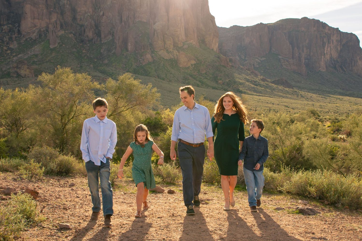Family walking together through desert landscape with mountain backdrop at golden hour.