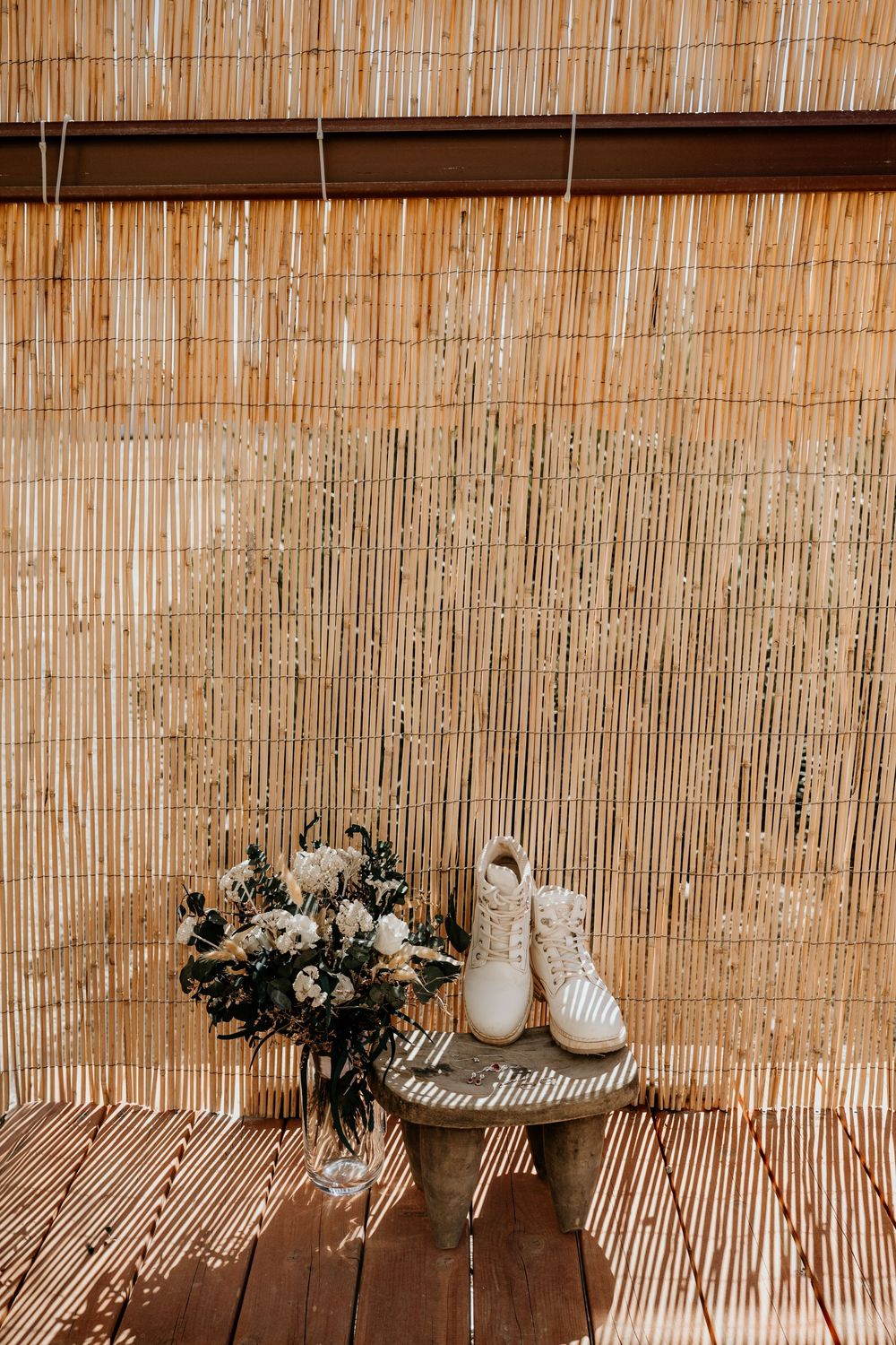 Wedding accessories and floral arrangement against bamboo backdrop.