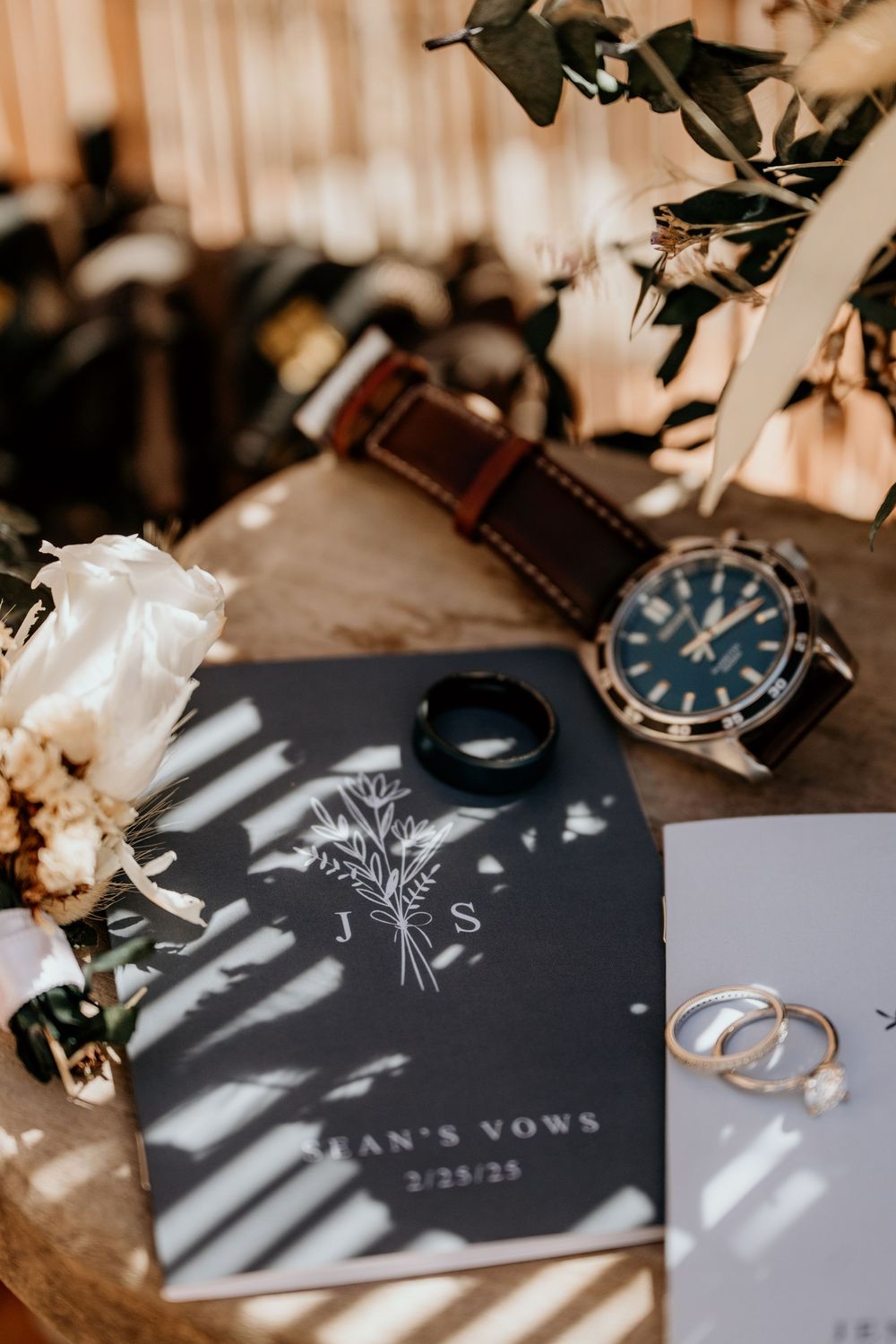 Wedding vow cards and watch arranged artistically with natural lighting and shadows.