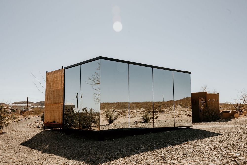 Modern minimalist mirrored building in desert landscape panoramic view.