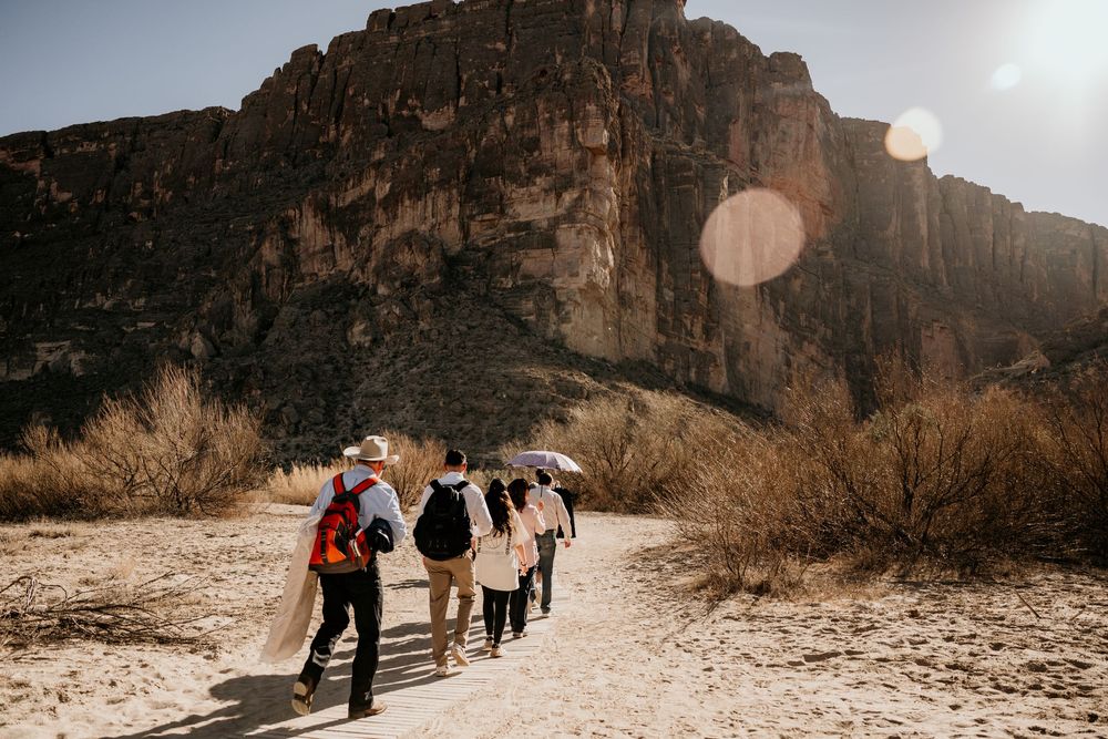 Desert canyon landscape with people walking along a winding trail.
