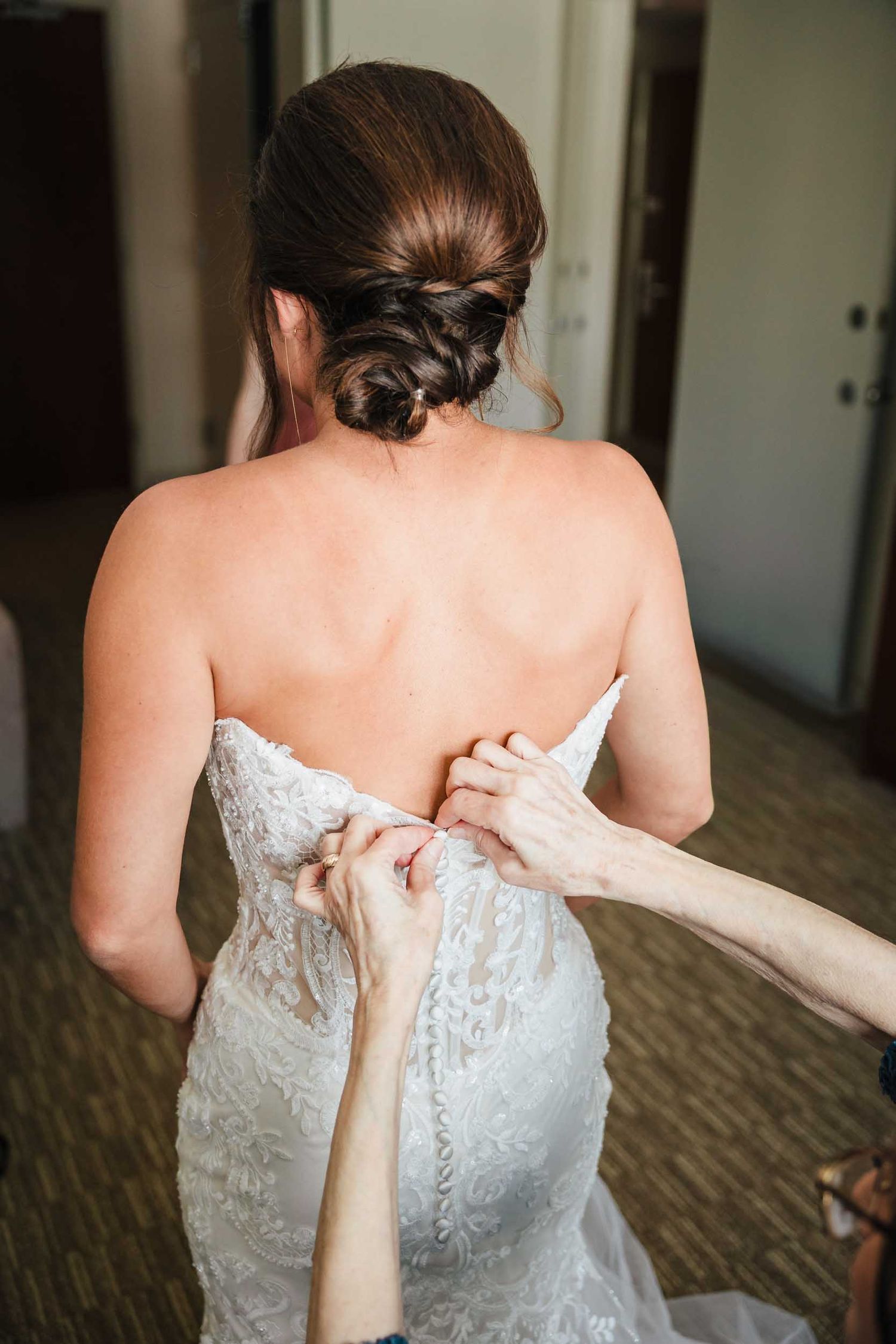 Bride having the back of her lace wedding dress buttoned during wedding morning preparations in Boston