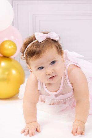 Baby photoshoot setup with pink and gold balloons against white backdrop.