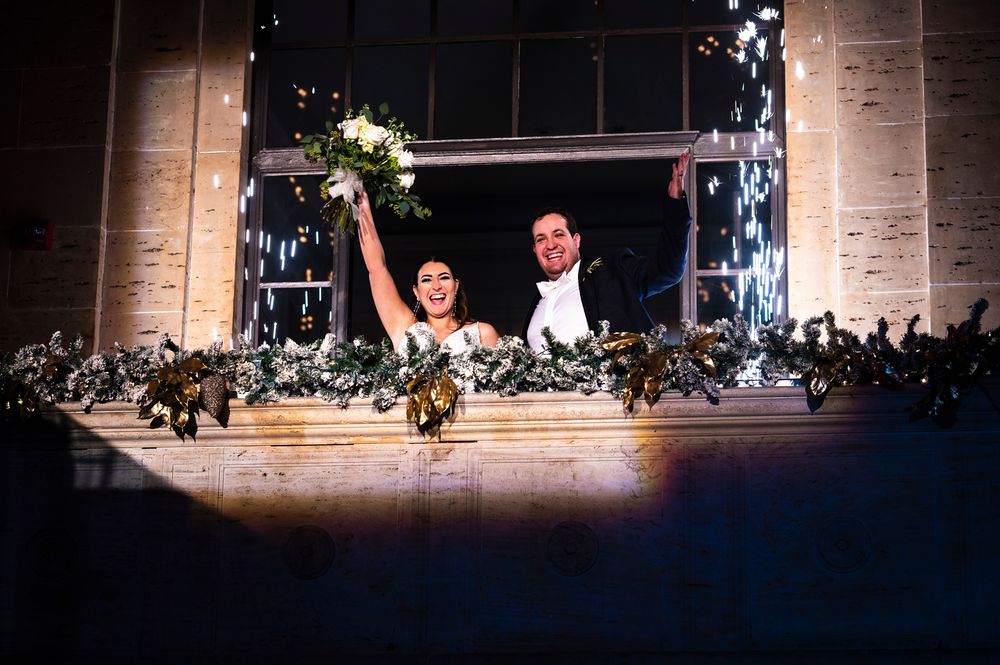 A couple performs an elegant dance lift during a stage performance with dramatic lighting and stone walls at a Union Trust wedding