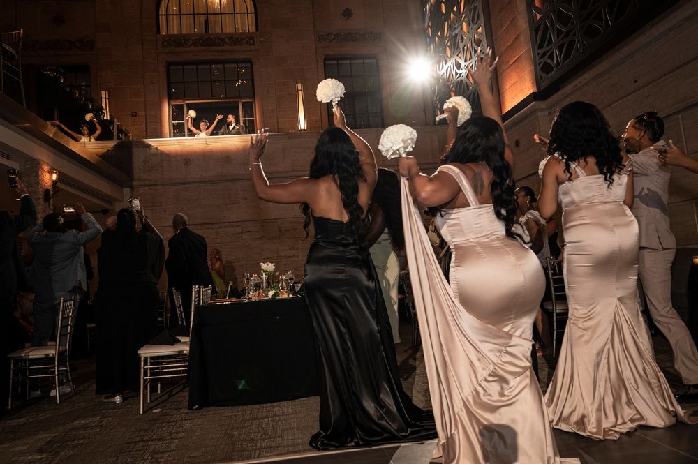 Wedding guests dance and celebrate on a dimly lit dance floor during an evening reception party.