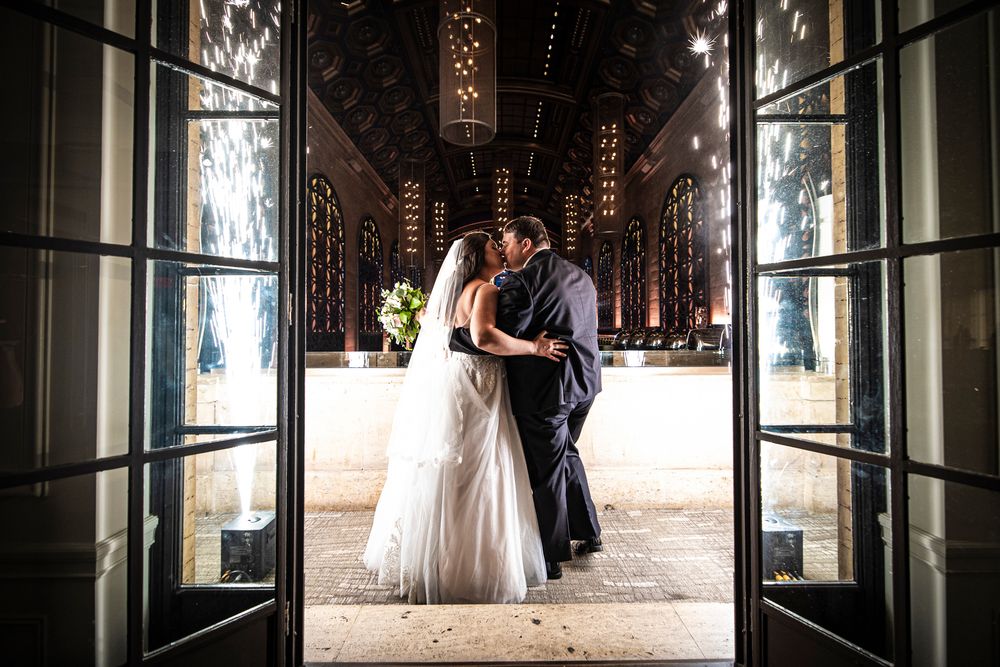A romantic wedding couple shares an intimate moment at a Union Trust wedding in an elegantly lit corridor and ornate architecture.