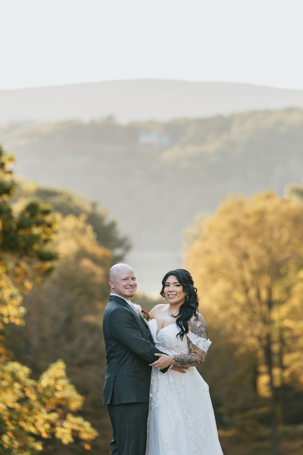 A couple shares a romantic moment during their autumn wedding photoshoot with golden foliage in the background.