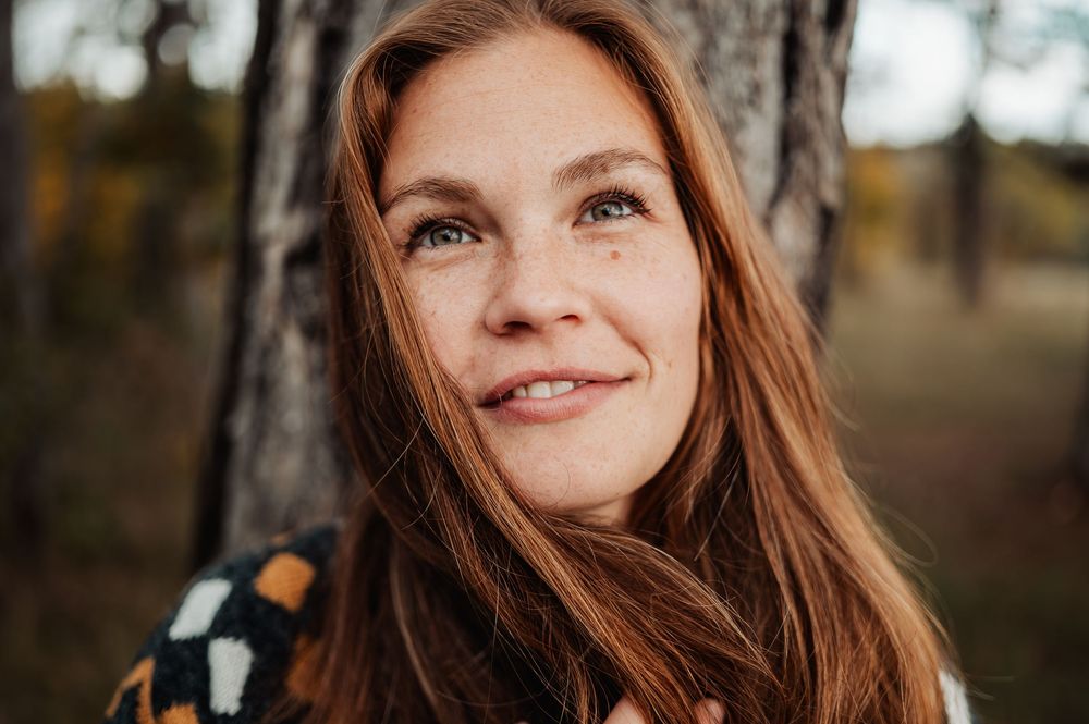A collection of seven outdoor portrait photos showing a person with long auburn hair in natural autumn lighting.