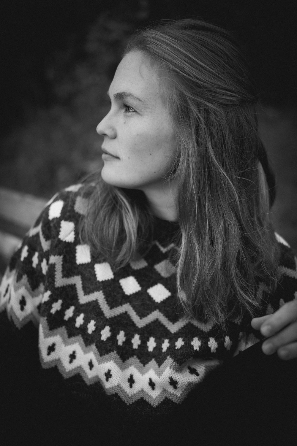 Black and white profile shot showing a knit sweater with geometric pattern and flowing hair.