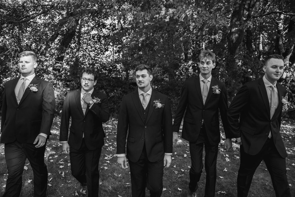 A wedding party poses together outdoors under blooming trees during a spring celebration.