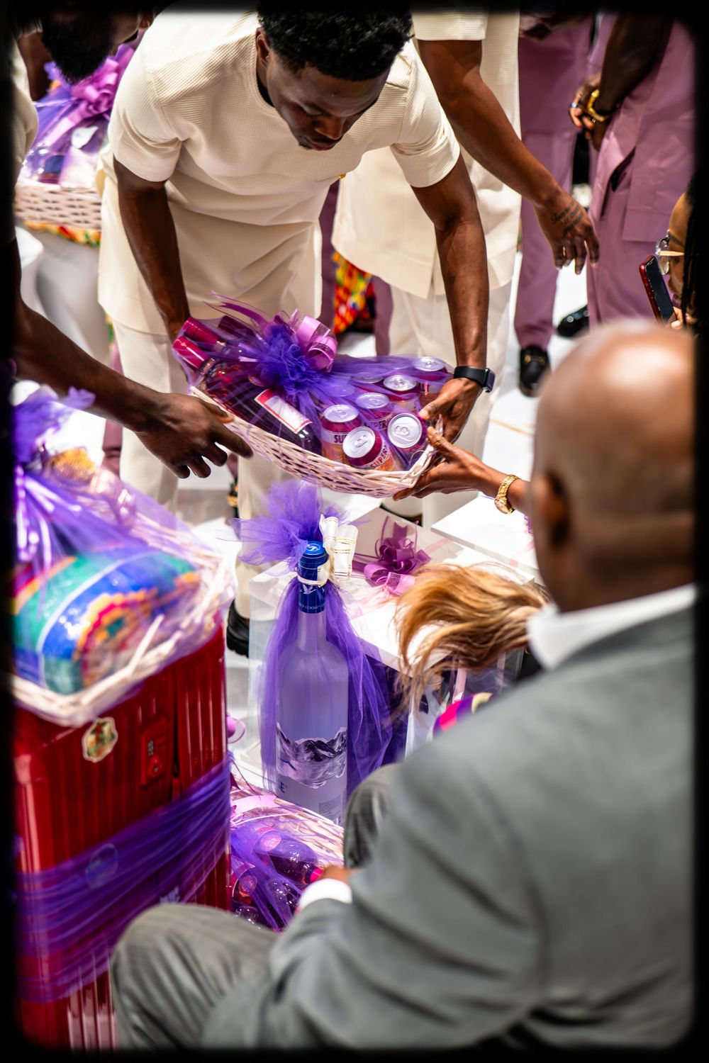 People examining purple-themed party supplies and decorative bottles at what appears to be a festive gathering or event.
